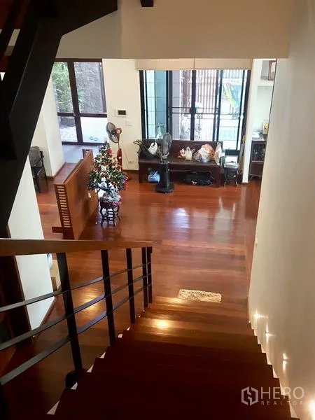Home Office for rent or sale in Bang Rak, Bangkok - View from the stair landing to an open-plan living area with polished wooden floors.