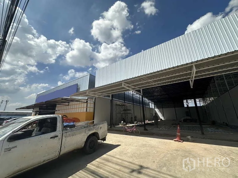 Warehouse for rent in Lam Luk Ka, Pathum Thani - Angled exterior of the warehouse showing metal canopy, loading area and driveway suitable for trucks