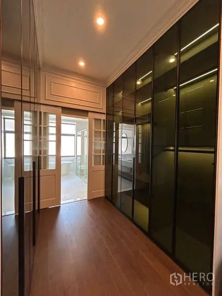 Detached House for sale in Bang Kapi, Bangkok - Hallway walk-in closet with floor-to-ceiling wardrobes leading to bathroom.