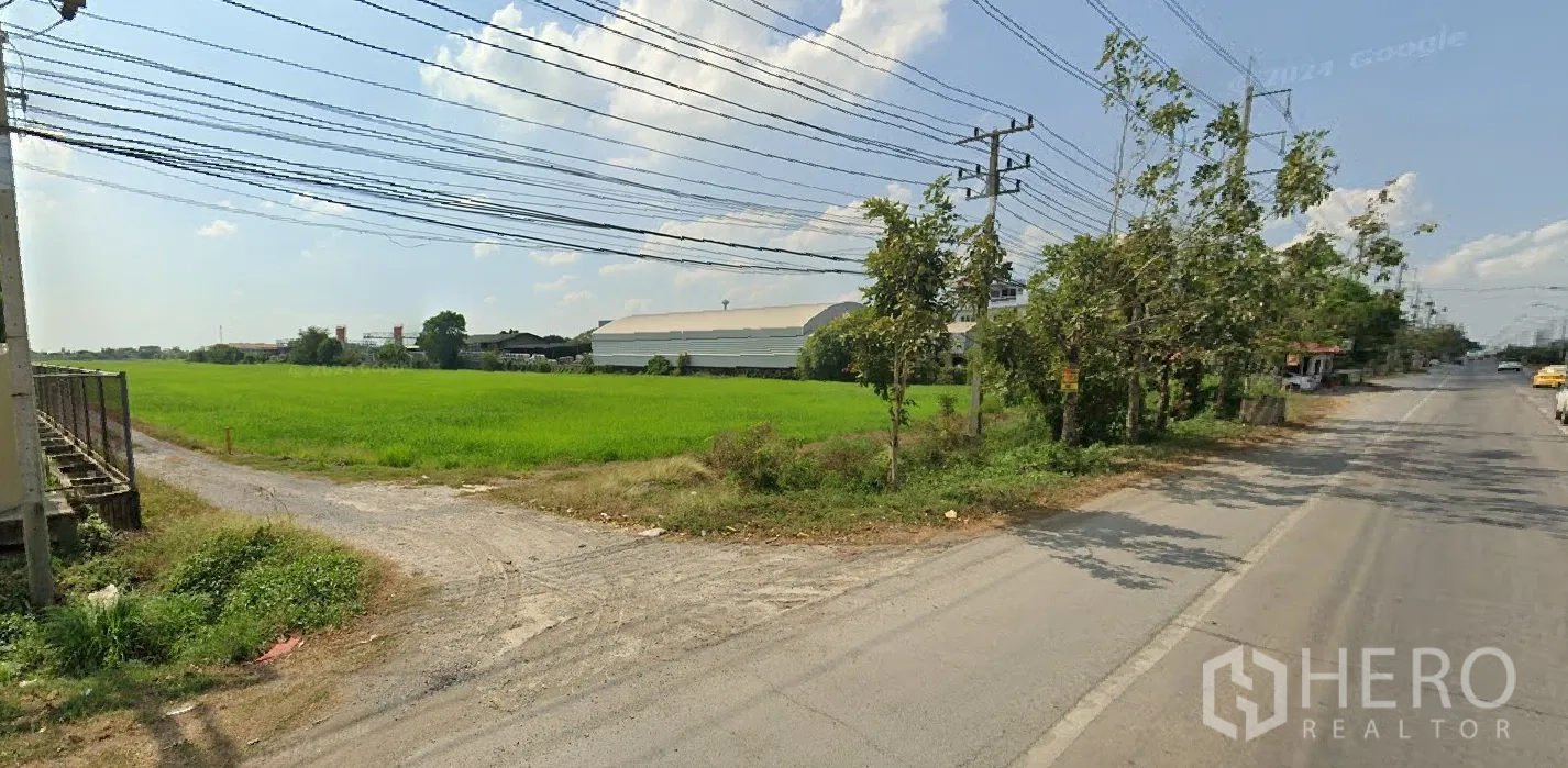 Land for sale in Lat Lum Kaeo, Pathum Thani - Gravel access point from the main road leading into the large flat green plot.