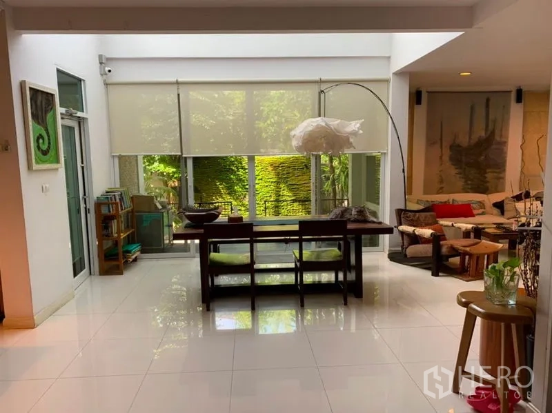 Detached House for sale in Suan Luang, Bangkok - Dining space beside sliding glass doors overlooking a green wall with an adjoining lounge corner.
