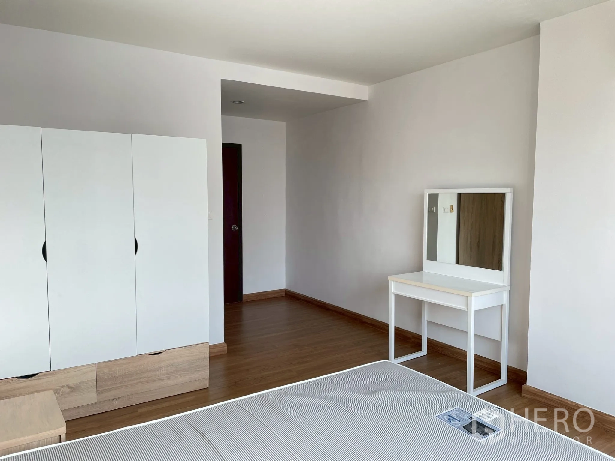 อพาร์ทเมนท์ for rent in Khlong Toei, Bangkok - ห้องนอนพร้อมตู้เสื้อผ้า โต๊ะเครื่องแป้งสีขาว และโต๊ะหัวเตียง