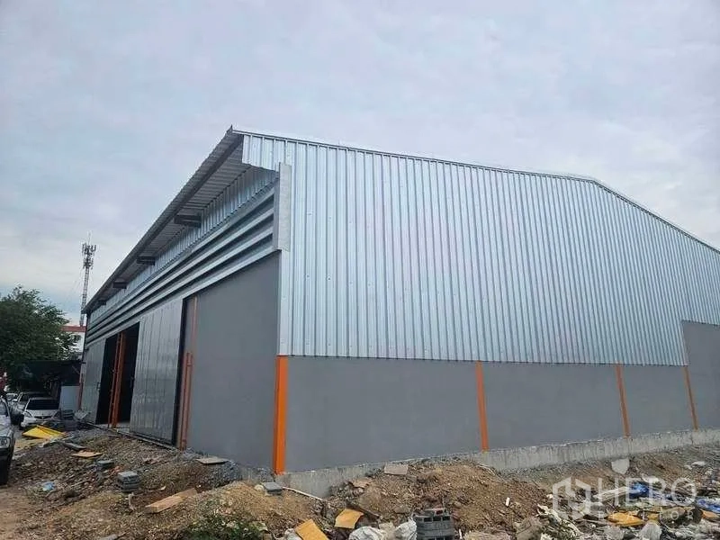 Warehouse for rent in Lam Luk Ka, Pathum Thani - Rear and side view of new metal-clad warehouse on raised concrete foundation.
