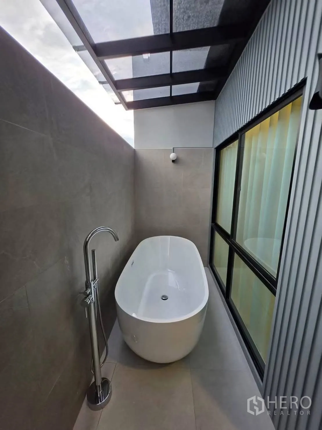 Townhouse for rent in Bang Phli, Samut Prakan - Freestanding bathtub on a covered terrace with a floor-mounted faucet and glass roof.