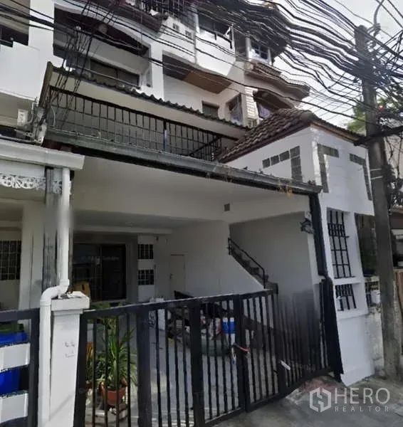 带办公室的家 出租在Khlong Toei, Bangkok - 联排式住办楼正面立面，黑色大门与有顶停车位。