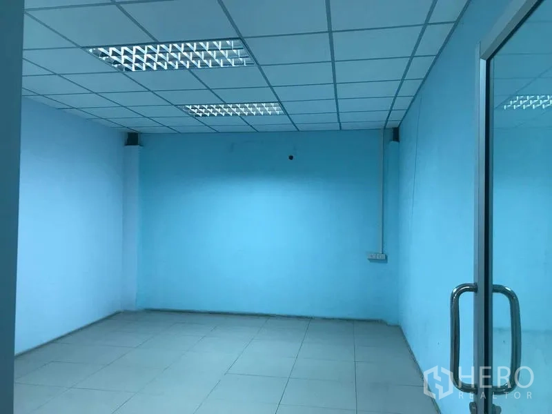 Warehouse for rent in Bang Phli, Samut Prakan - Compact blue office or meeting room with tiled floor, drop ceiling, and glass door.