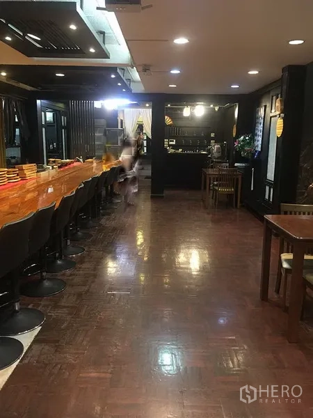 Retail Space for rent in Khlong Toei, Bangkok - Long wooden bar counter with stools, downlights and polished wood flooring inside the venue.