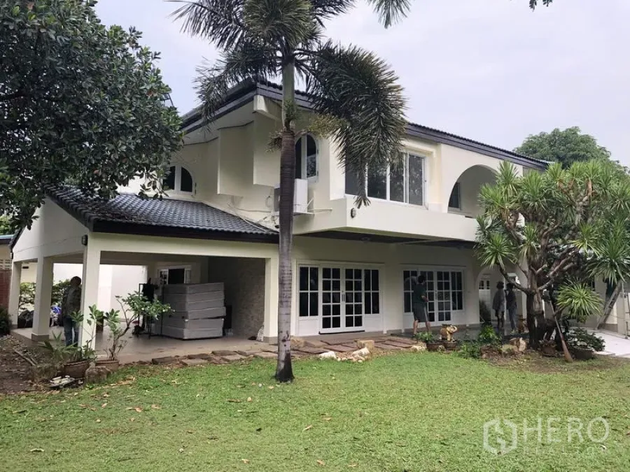 Detached House for rent in Khan Na Yao, Bangkok - Two-storey detached house with white facade, covered terrace and a large green lawn with mature palms.