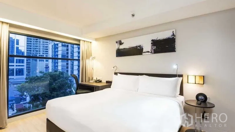 อพาร์ทเมนท์ ให้เช่าในWatthana, Bangkok - ห้องนอนพร้อมหน้าต่างบานใหญ่ เตียงควีน และวิวตึกเมือง.