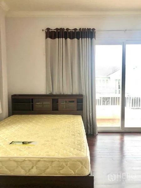 独立式住宅 出售在Lat Krabang, Bangkok - 采光充足的卧室，带阳台通道、深色木地板和内置床头柜。