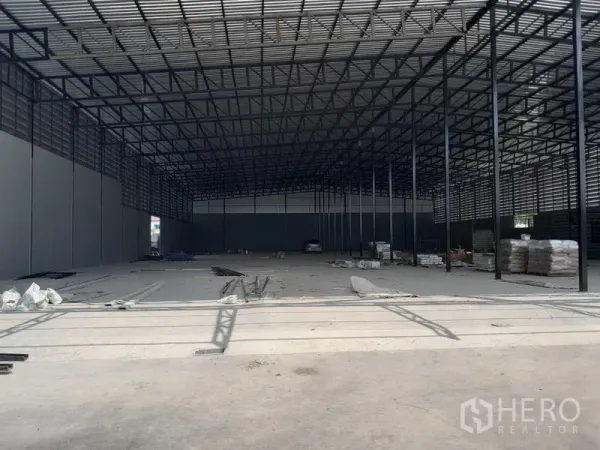 Warehouse for rent in Lam Luk Ka, Pathum Thani - Expansive warehouse interior with steel truss roof, high clearance and concrete floor under fit‑out.