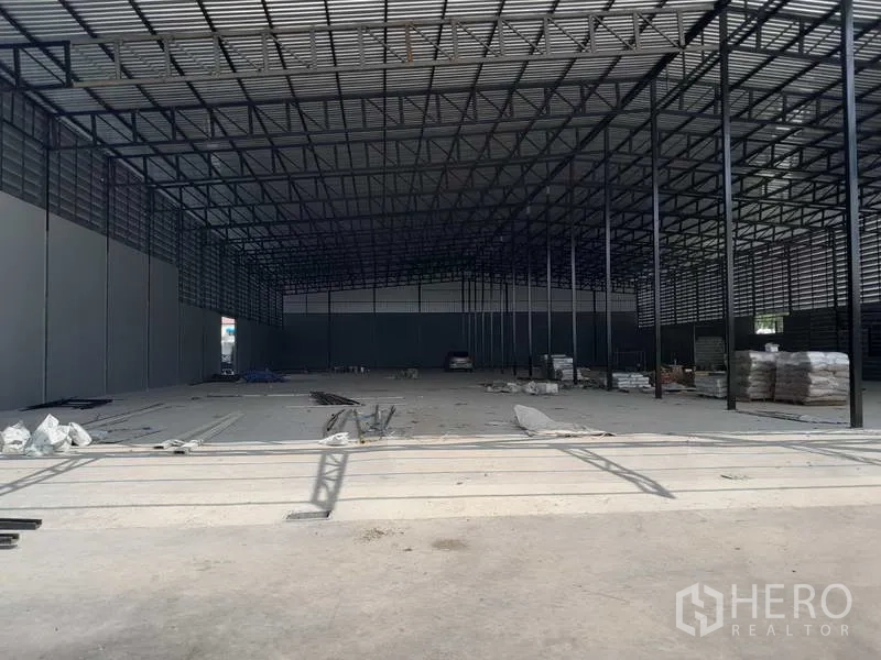 Warehouse for rent in Lam Luk Ka, Pathum Thani - Expansive warehouse interior with steel truss roof, high clearance and concrete floor under fit‑out.