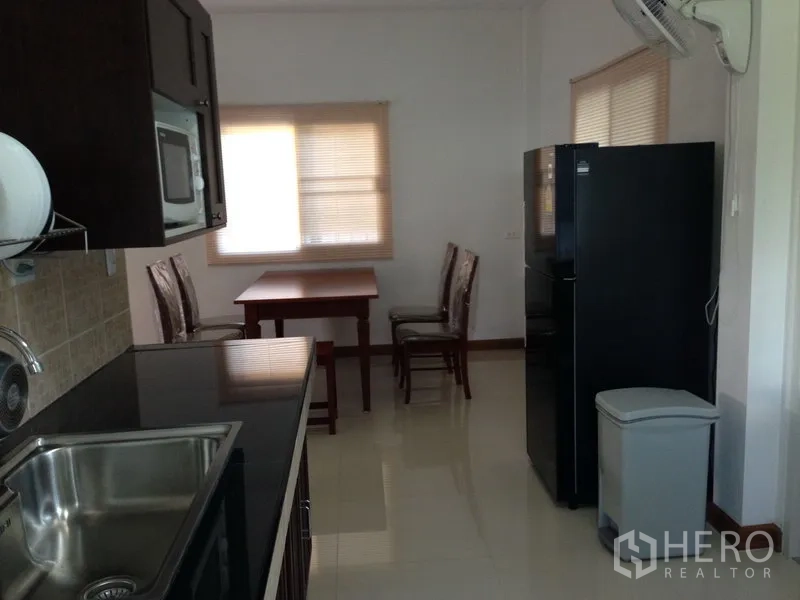 Detached House for sale in Phra Khanong, Bangkok - Fitted kitchen with black countertops, stainless sink, upper cabinets, fridge and dining nook.