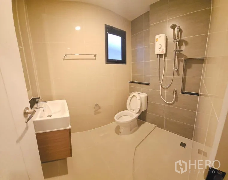 Detached House for rent in Saphan Sung, Bangkok - Bright tiled bathroom with walk-in shower, water heater, toilet and floating vanity.