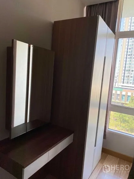 Condominium for rent in Phra Khanong, Bangkok - Wardrobe and vanity beside a window overlooking nearby buildings.