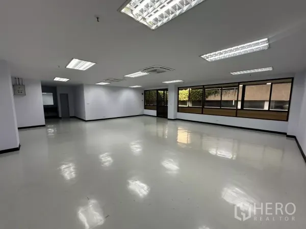 办公空间 出租 - 宽敞的空置办公区，可见玻璃入口门与整面窗墙，地面光洁。