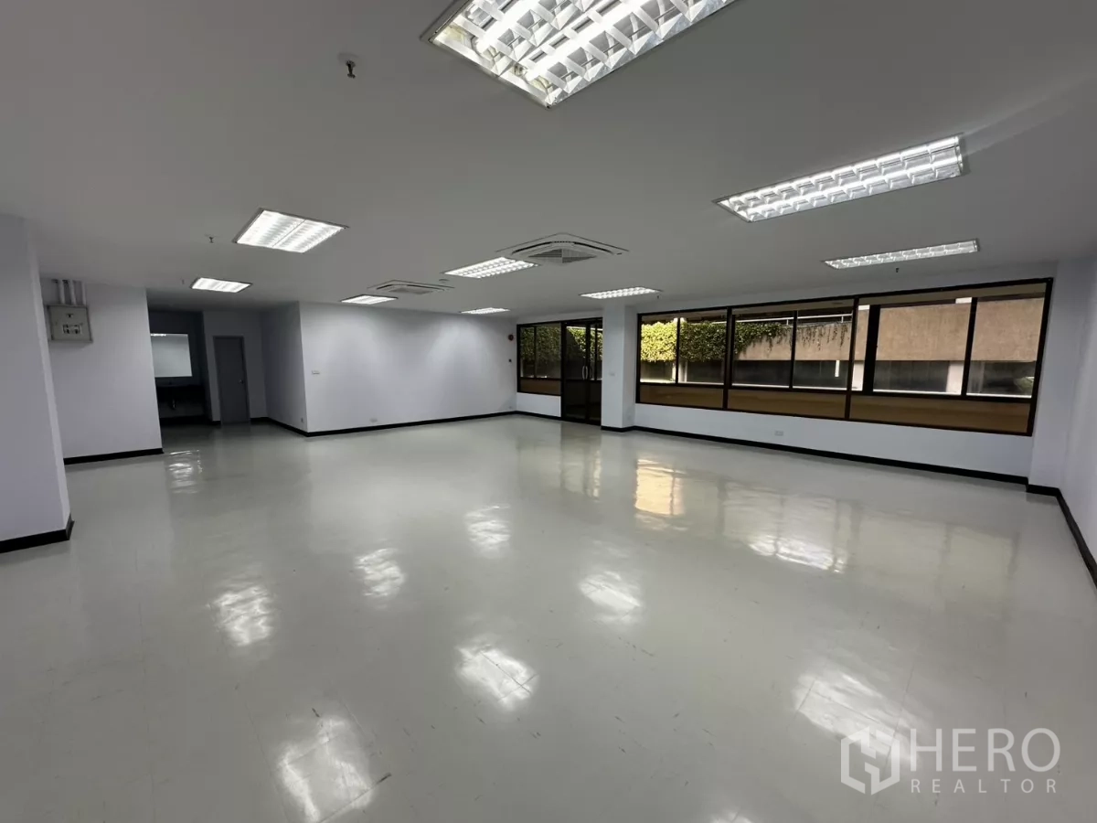 办公空间 出租 - 宽敞的空置办公区，可见玻璃入口门与整面窗墙，地面光洁。