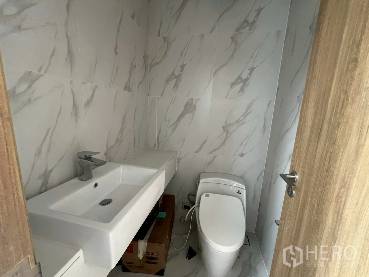Retail Space for rent - Modern restroom with marble-look tiles, basin, and toilet.