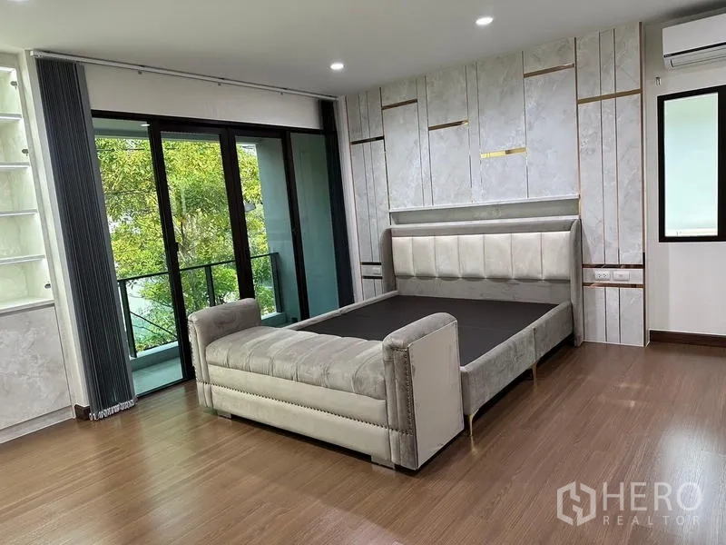 Detached House for sale in Saphan Sung, Bangkok - Spacious master bedroom with upholstered bed and balcony access.