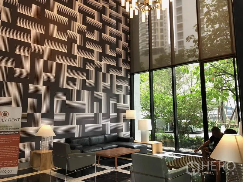 Condominium for rent in Khlong Toei, Bangkok - Double-height lobby featuring patterned accent wall, chandeliers and lounge seating.