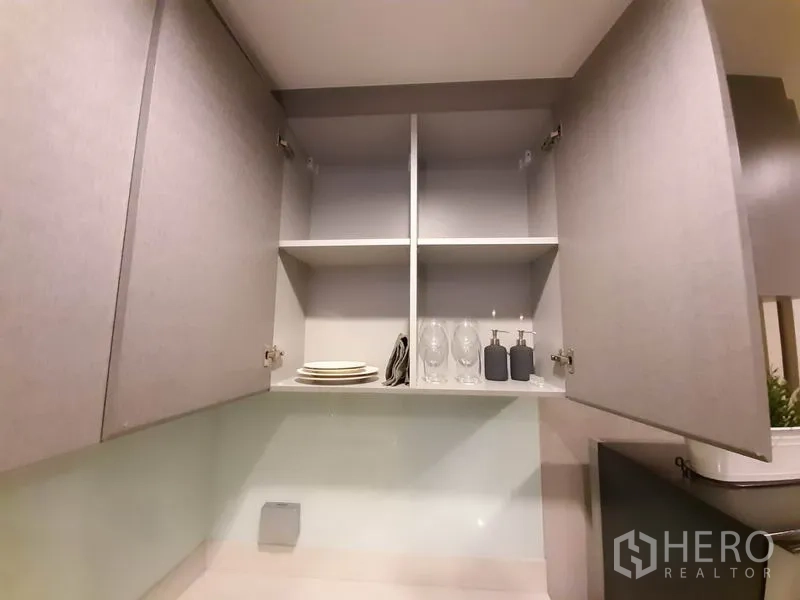 Condominium for rent or sale in Khlong Toei, Bangkok - Open shelving in the kitchen with plates and glassware neatly arranged.