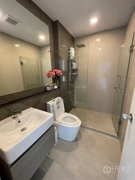 Condominium for sale - Contemporary bathroom with large mirror, glass-enclosed shower and vanity storage.