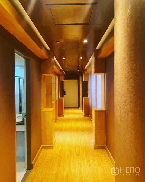 Condominium for rent in Watthana, Bangkok - Condominium corridor finished in warm wood tones with ceiling spotlights.