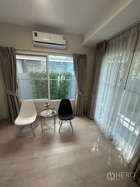 独立式住宅 出租在Prawet, Bangkok - 明亮的角落会客区，大窗、纱帘与木地板。