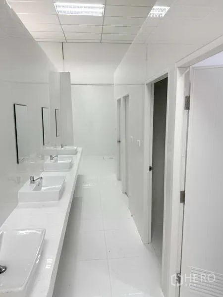 工厂 出租在Pathum Thani - 整洁的公共卫生间走廊，多个洗手盆与隔间。