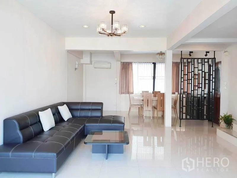 Detached House for rent in Phra Khanong, Bangkok - Spacious open-plan lounge with chandelier and L-shaped sofa facing the dining zone.