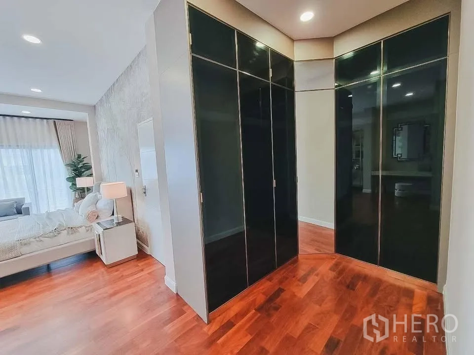 独栋房屋 for rent or sale in Bang Phli, Samut Prakan - 步入式衣帽间，黑色亮面柜体通向木地板卧室。