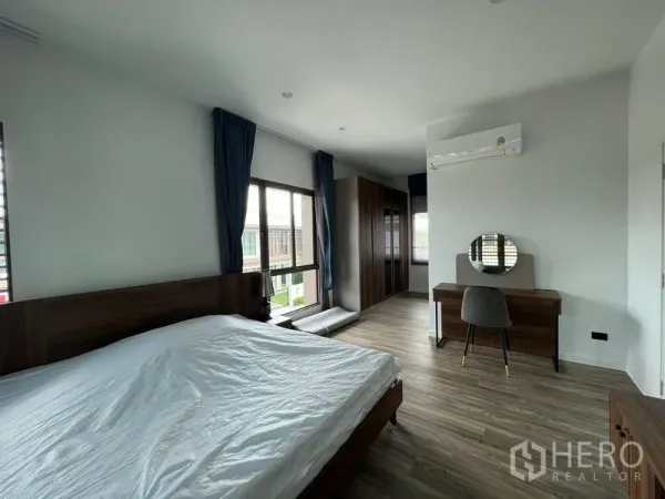 Detached House for rent in Bang Kapi, Bangkok - Master bedroom angle showing desk, wardrobe cabinetry and wall-mounted air conditioner.