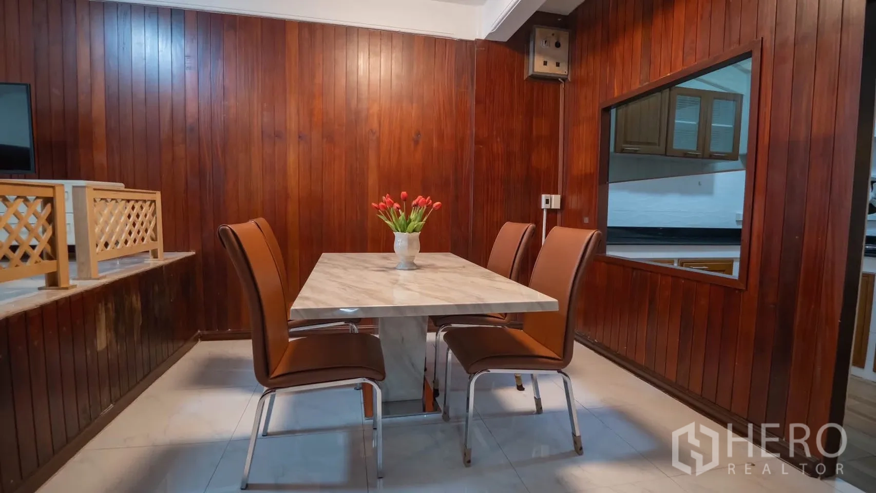 ทาวน์เฮาส์ for rent in Watthana, Bangkok - ห้องรับประทานอาหารโต๊ะหน้าหินอ่อนกับเก้าอี้สี่ตัว ผนังไม้และช่องเสิร์ฟอาหารไปครัว