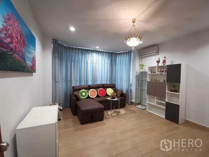 บ้าน ให้เช่าในPrawet, Bangkok - ห้องนั่งเล่นอบอุ่น โซฟาหนังเข้ามุม ผ้าม่านสีน้ำเงิน โคมไฟระย้า แอร์ และชั้นวางของ