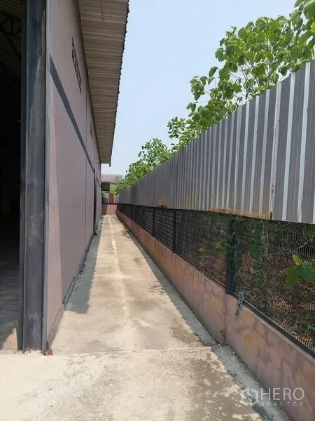 货栈 出租在Pathum Thani - 仓库外侧通道，配金属围栏与绿植。