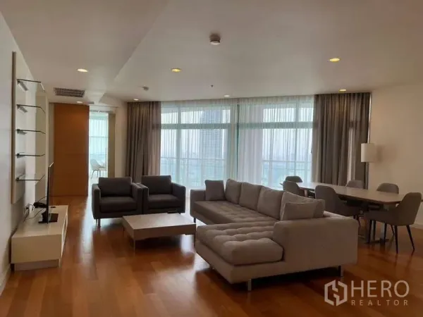 公寓 出租在Bang Kho Laem, Bangkok - 宽敞客厅，L 型沙发、单人椅、餐桌与落地窗。