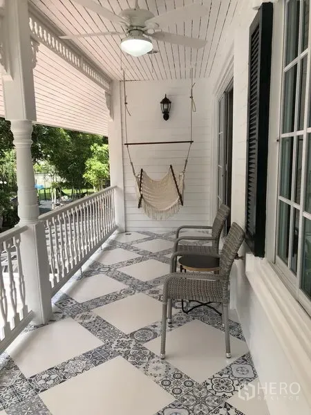 Detached House for rent in Mueang Samut Prakan, Samut Prakan - Covered upper balcony with patterned tiles, railing, ceiling fan, hammock chair and wicker seats.