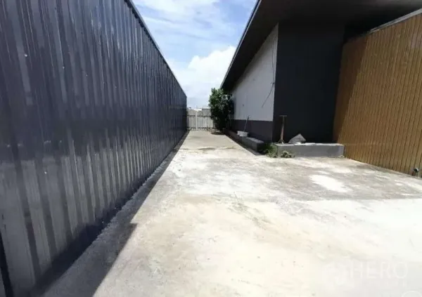 Warehouse for rent in Prawet, Bangkok - Long concrete driveway between warehouse and office leading to a rear gate for truck access.