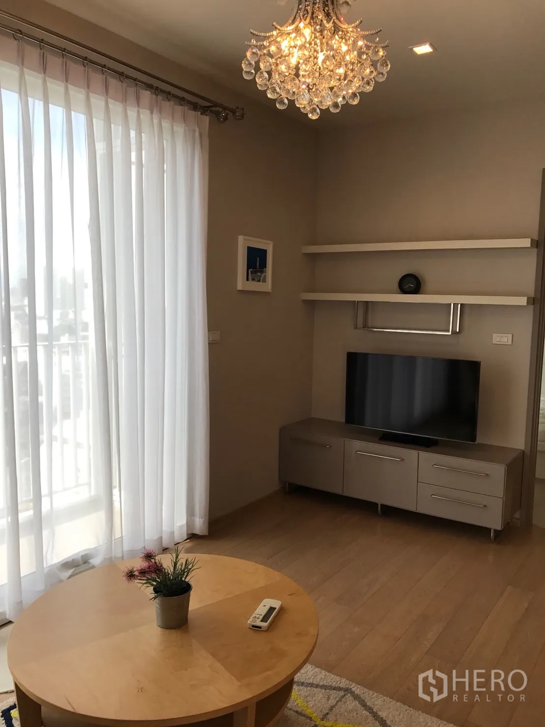 Condominium for rent or sale in Watthana, Bangkok - TV corner with media console, floating shelves and floor-to-ceiling curtains.