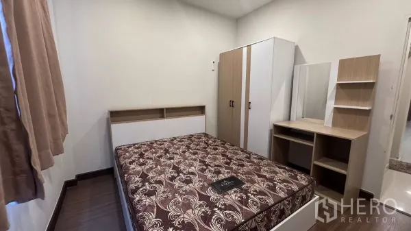 Detached House for rent or sale in Saphan Sung, Bangkok - Compact furnished bedroom featuring a double bed, wardrobe and dressing table with neutral walls and wood flooring.