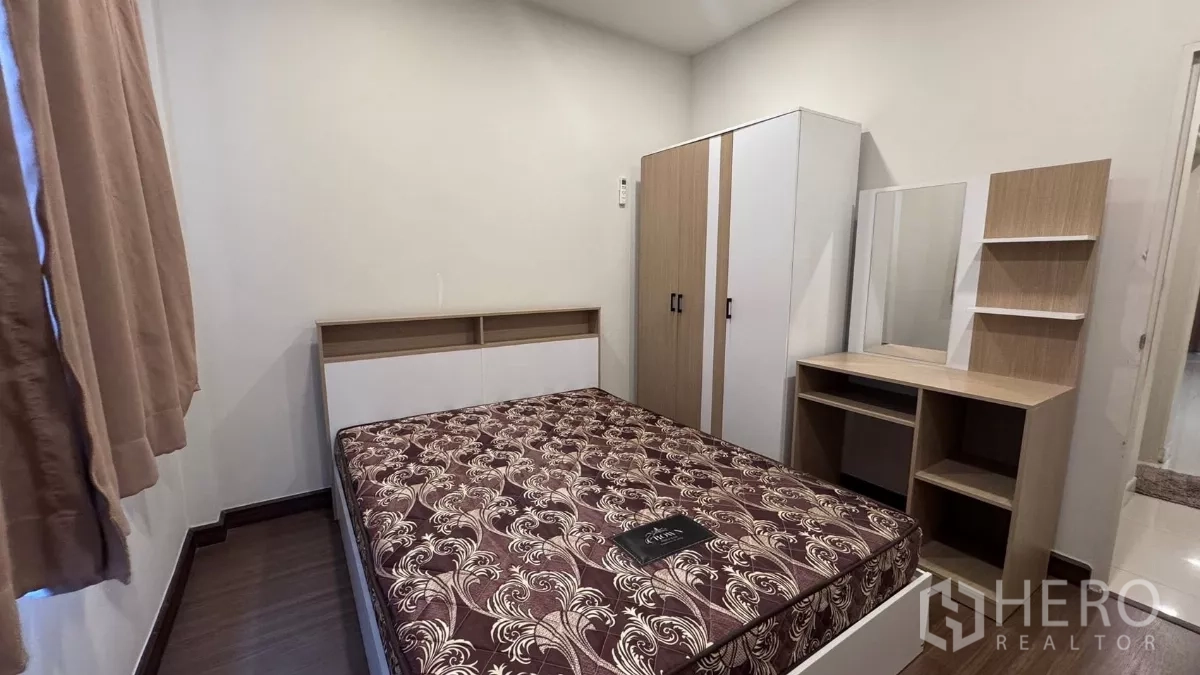 Detached House for rent or sale in Saphan Sung, Bangkok - Compact furnished bedroom featuring a double bed, wardrobe and dressing table with neutral walls and wood flooring.