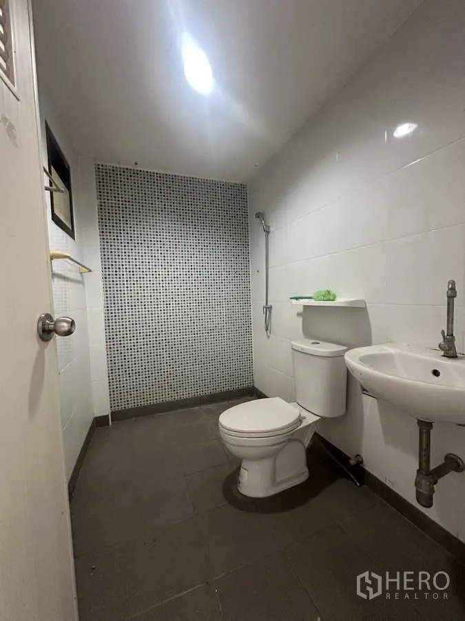 Warehouse for rent or sale in Bang Yai, Nonthaburi - Clean restroom with toilet, sink and tiled walls inside the warehouse office.