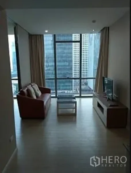 Condominium for rent in Watthana, Bangkok - Open-plan lounge with sofa and TV unit looking toward a wall of windows and skyline views.