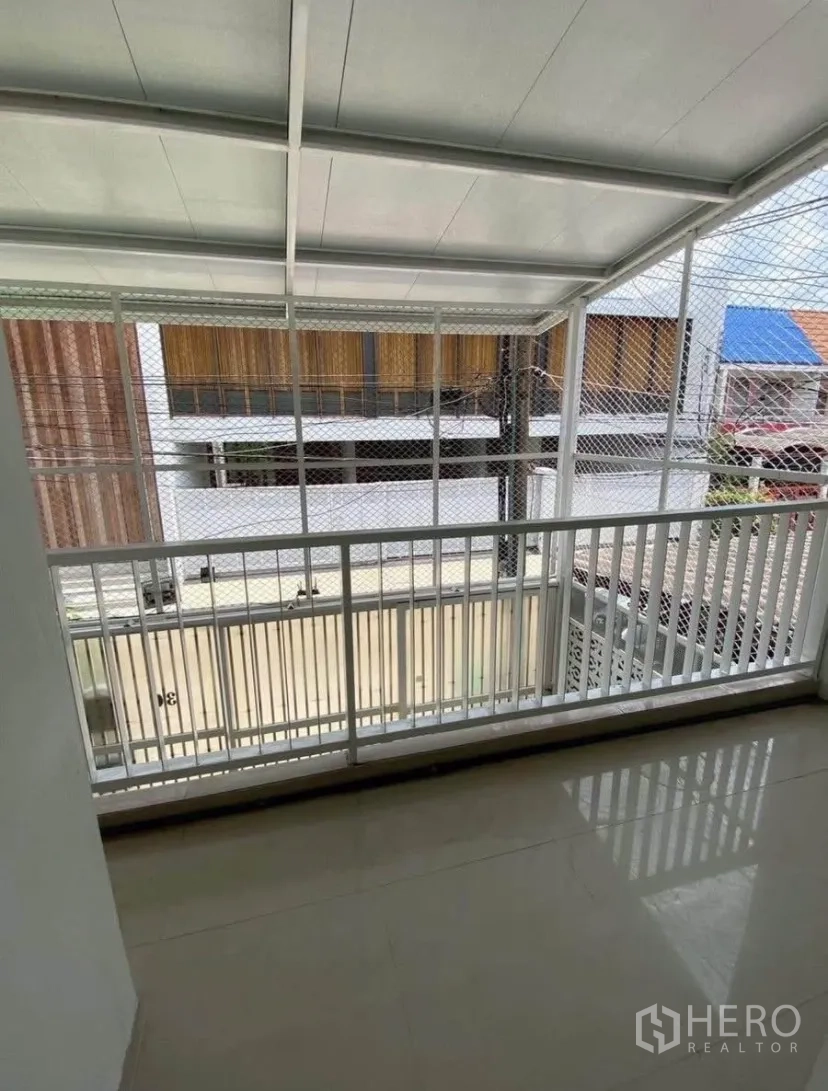 ทาวน์เฮาส์ for rent in Phra Khanong, Bangkok - ระเบียงมีหลังคาพร้อมราวสีขาวและตาข่ายนิรภัย มองเห็นซอยด้านหน้า