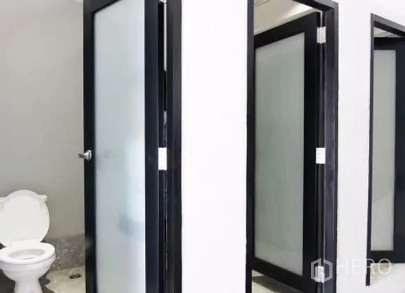 Retail Space for rent in Khlong Toei, Bangkok - Close-up of toilet cubicles with frosted glass doors and a white toilet.