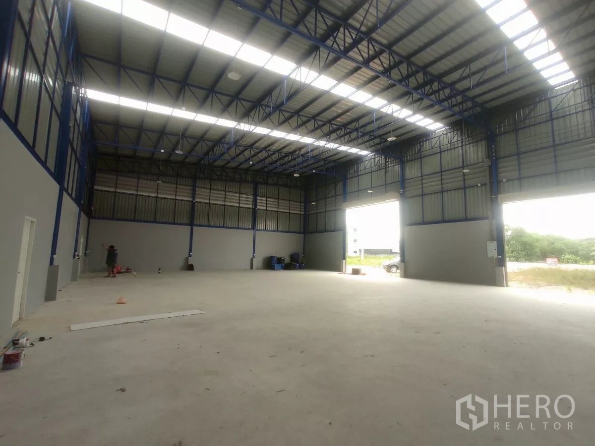 Factory for sale in Khlong Toei, Bangkok - Open factory floor with concrete slab, skylit roof and twin roller doors to the outside.