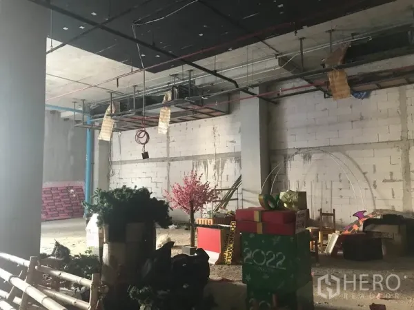 พื้นที่ขายปลีก ให้เช่าในKhlong Toei, Bangkok - มุมมองกว้างของร้านค้ายังไม่ตกแต่ง มีท่อแขวน เสาคอนกรีต และของตกแต่งวางไว้.