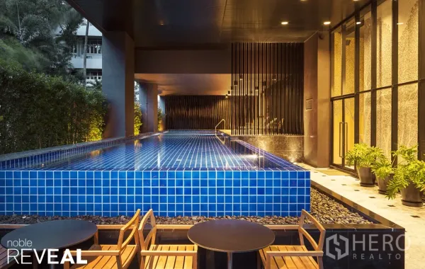 Condominium for rent in Watthana, Bangkok - Condominium facilities featuring a modern blue‑tiled swimming pool with seating area and greenery.