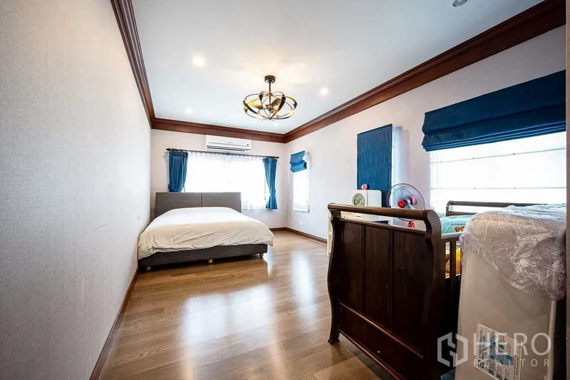 独立式住宅 出售在Prawet, Bangkok - 宽敞卧室，木地板、蓝色窗帘与空调照明。