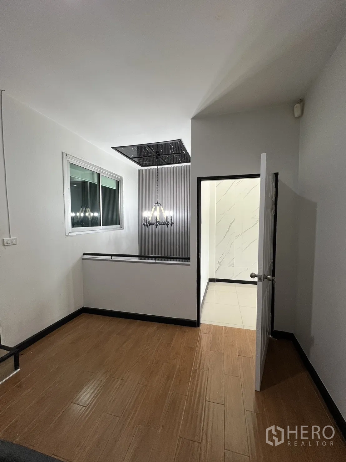 联排别墅 for rent in Watthana, Bangkok - 楼层过道，木地板，窗户与吊灯，靠近楼梯。
